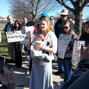 A group of protesters with signs and a bullhorn