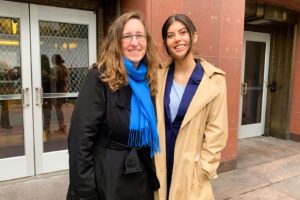 Two attorneys posing smiling in front of a courthouse. 