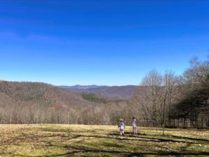 A wide view of mountains, with two toddler-aged children standing in the foreground.